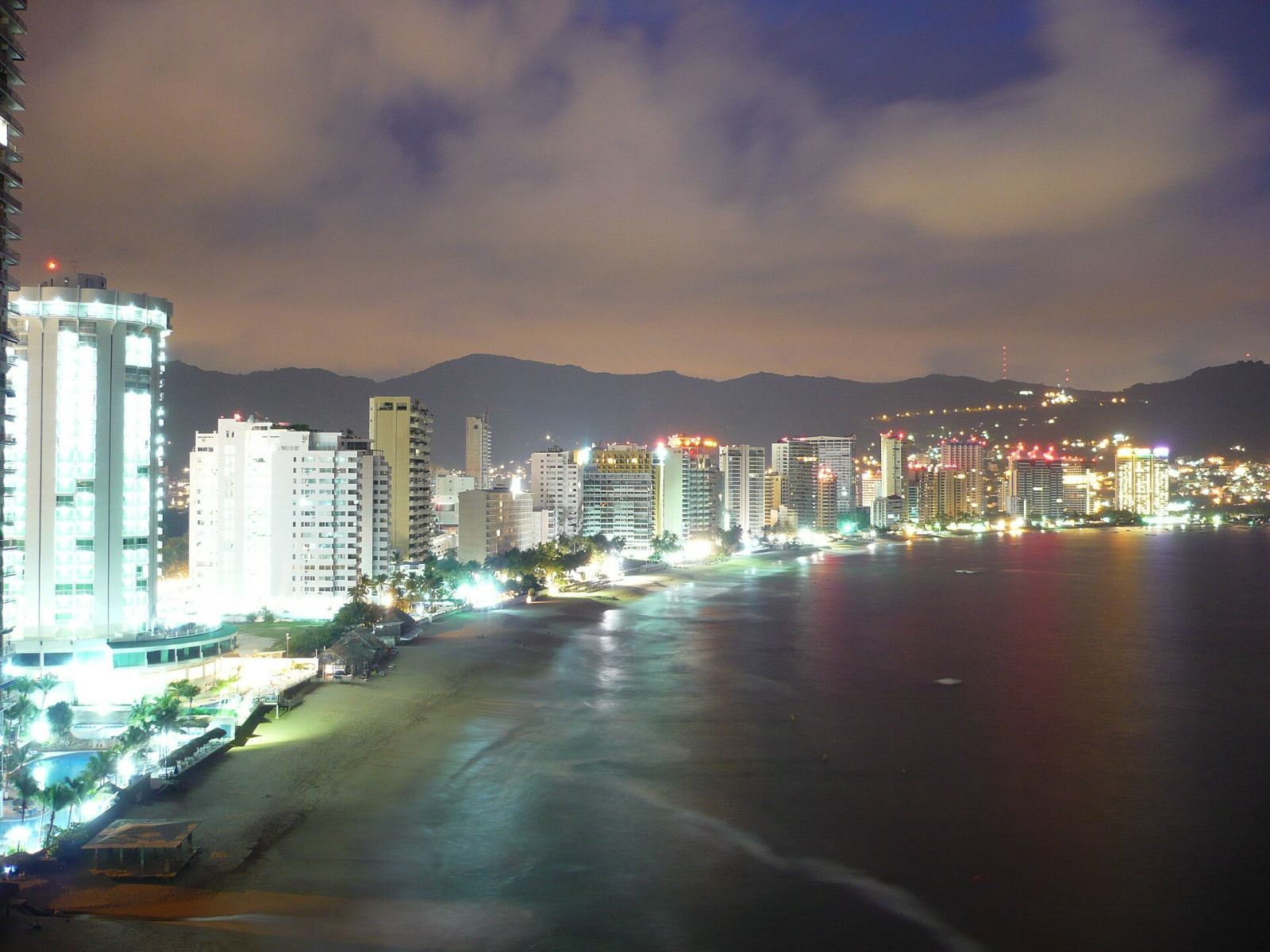 Acapulco’s bay at night, hotel towers lit along the beach